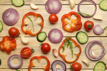 Ingredients for cooking salad. background from Various vegetables and spices carrot, tomato, onion, cucumber, pepper and arugula on a natural wooden table. top view.