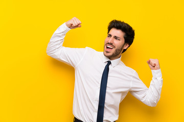 Fototapeta premium Businessman on isolated yellow background celebrating a victory