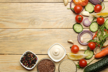 Ingredients for cooking salad. Various vegetables and spices carrots, tomatoes, onions, cucumbers, peppers and arugula on a natural wooden table. top view.