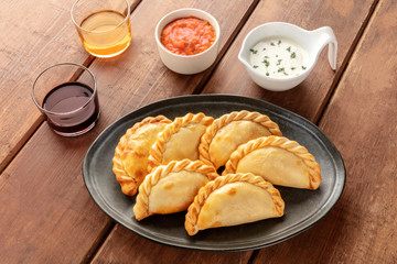 Empanadas with sauces and wine on a dark rustic wooden background