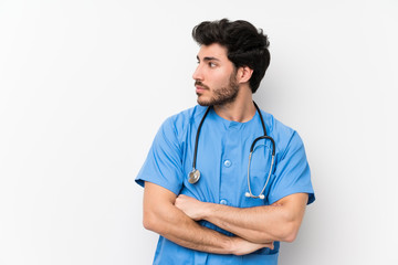 Surgeon doctor man over isolated white wall standing and looking side