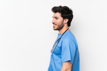 Surgeon doctor man over isolated white wall standing and looking to the side