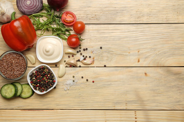 Ingredients for cooking salad. Various vegetables and spices carrots, tomatoes, onions, cucumbers, peppers and arugula on a natural wooden table. top view.