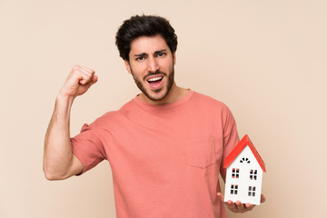 Handsome man holding a little house