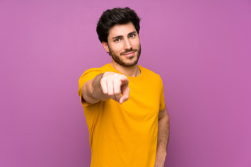 Fototapeta premium Handsome over isolated purple wall points finger at you with a confident expression