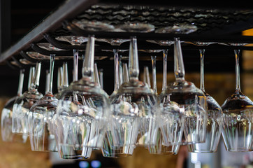 Rows of clean empty glasses above the bar counter. Interior of pub, bar or restaurant