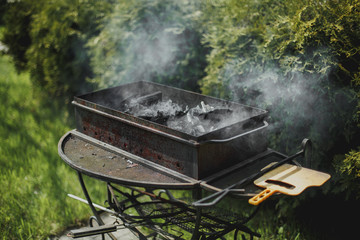 black brazier with smoking coals in summer garden