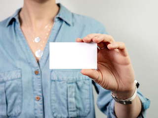 Female hand hold blank white card mockup. Plain call-card mock up template holding woman arm. Caucasian woman in casual blue denim shirt with business card display front. Check offset card design