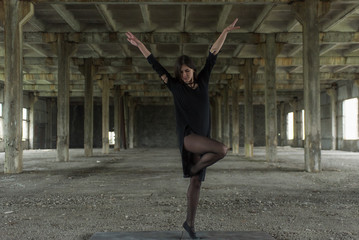 Young girl is sympathetic emotional doing exercises acrobatic movements, are in the premises of an old factory, warehouse, acro