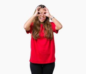 Obraz na płótnie Canvas Young beautiful brunette woman wearing red t-shirt over isolated background doing ok gesture like binoculars sticking tongue out, eyes looking through fingers. Crazy expression.