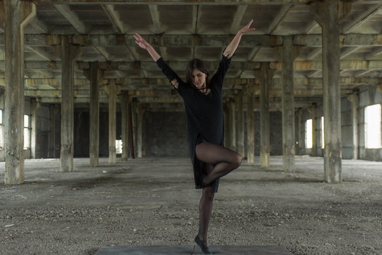 Young girl is sympathetic emotional doing exercises acrobatic movements, are in the premises of an old factory, warehouse, acro