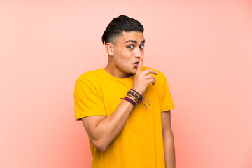 Young man with yellow shirt over isolated pink wall doing silence gesture