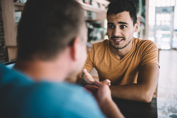Serious male colleagues discussing information for startup project sitting at cafeteria table and feeling confused on fresh ideas, Caucasian men brainstorming togetherness in coworking space