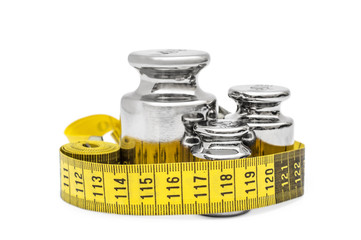 Metal weights with measuring tape on white.