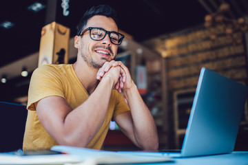 Portrait of cheerful male it professional working remotely with modern laptop device sitting at...