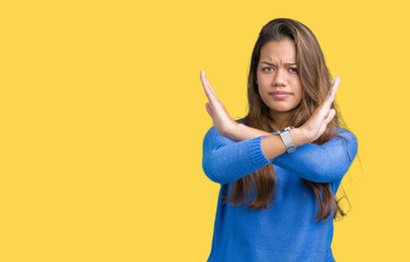 Young beautiful brunette woman wearing blue sweater over isolated background Rejection expression crossing arms doing negative sign, angry face