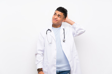 Fototapeta premium Young doctor man over isolated white wall having doubts and with confuse face expression