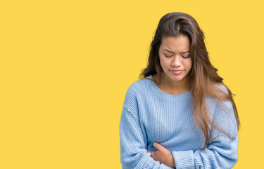 Fototapeta premium Young beautiful brunette woman wearing blue winter sweater over isolated background with hand on stomach because indigestion, painful illness feeling unwell. Ache concept.
