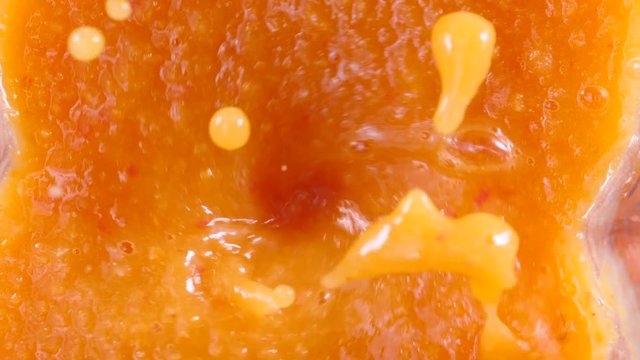 Making healthy shake cocktail. Close up blender jar with red orange color smoothie fruits vegetables mixture. Blended ingredients spinning in slow motion