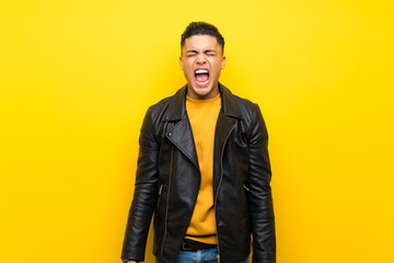 Fototapeta premium Young man over isolated yellow background shouting to the front with mouth wide open