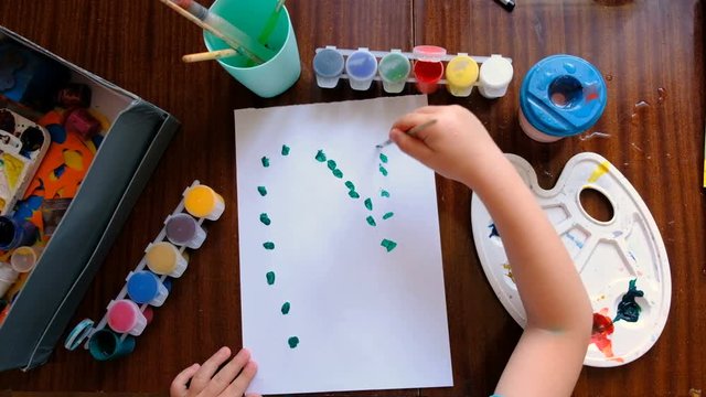A Small Child/Boy Draws With Paints On A Sheet Of Paper