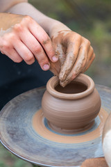 Potter's hands making clay pot.