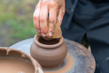 Potter's hands making clay pot.