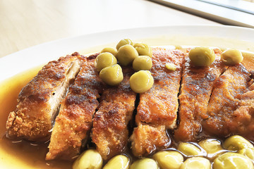 Selective focus closeup on deep fry slice crispy pork ribs Chinese delicious food with green peas and gravy on white plate in Chinese restaurnt.