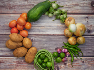 Many fresh vegetables are placed on a wooden table.