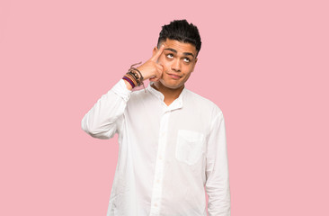 Young man making the gesture of madness putting finger on the head on colorful background