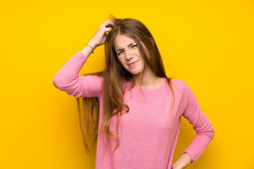 Young woman with long hair over isolated yellow wall having doubts while scratching head