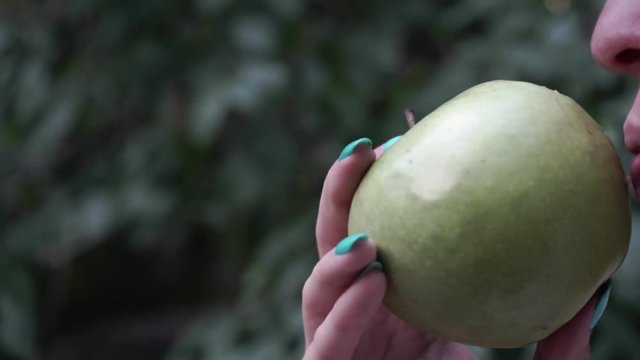 girl biting a green apple. women's teeth bite the apple. bitten green apple close up.