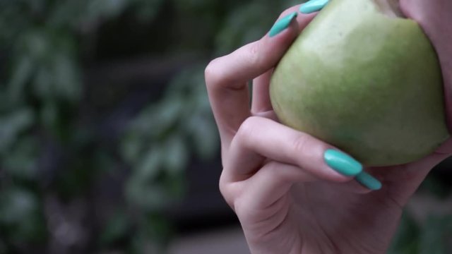 girl biting a green apple. women's teeth bite the apple. bitten green apple close up.