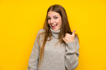 Young woman with long hair over yellow background making phone gesture