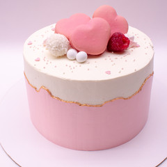 Delicate pink cake decorated with hearts and berries. On a white background.