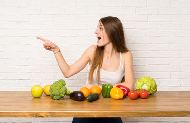 Young woman with many vegetables pointing finger to the side
