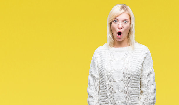 Young beautiful blonde woman wearing winter sweater and glasses over isolated background afraid and shocked with surprise expression, fear and excited face.