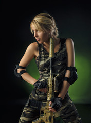 Fototapeta na wymiar the girl in military special clothes posing with a gun in his hands on a dark background in the haze