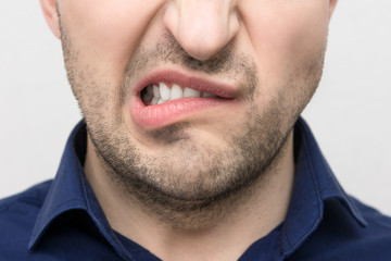 Obraz premium Grimace of irritation or discontent on the face of a young bearded man, close up, the concept of human emotion,emotions