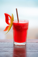 Glass Cup with a cool red cocktail. Butterfly figurine of watermelon on the edge of the glass.