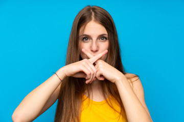 Young woman with long hair over isolated blue wall showing a sign of silence gesture