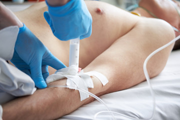 nurse's hands in blue latex gloves perfoming injection of propofol to patient for iv anesthesia