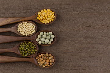 collection set of urad dal, beans, green peas, lentils, rice in wooden spoons.