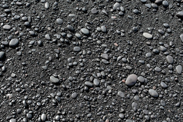 Wet black pebbles from black sand beach of Reynisfjara beach in Iceland