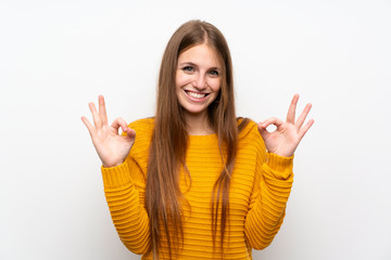 Young woman with yellow over isolated white wall showing an ok sign with fingers