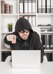 Man hacker showing by finger on you in office. Focus on hand