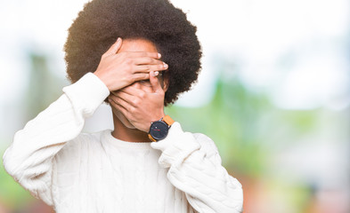 Young african american man with afro hair wearing glasses Covering eyes and mouth with hands, surprised and shocked. Hiding emotion