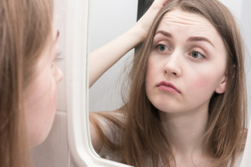 Sleepy girl's reflection in the mirror, sorrow on the face of a young woman, close up