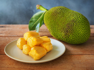Ripe jackfruit flesh in white plate on wooden table for tropical fruit or meat substitute concept.