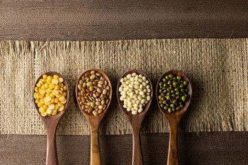 collection set of urad dal, beans, green peas, lentils, rice in wooden spoons.